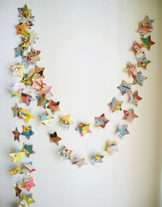 a necklace made out of folded origami stars hanging on a wall in a room