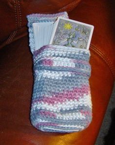 a crocheted purse sitting on top of a brown leather couch next to a magazine