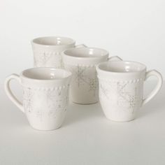 four white mugs sitting next to each other on top of a table with snowflakes