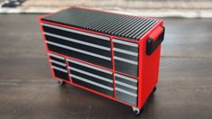 a red and black tool box sitting on top of a wooden table next to a rug