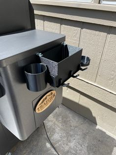 an outdoor grill with two cups on the burner and one cup in the holder