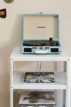 an old record player sitting on top of a white table next to a wall clock