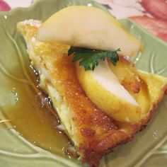 a piece of food on a green plate with sauce and apple slices in the center