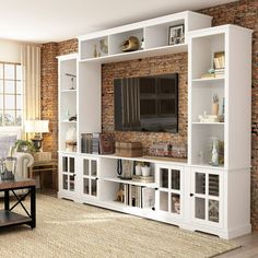 a living room with brick wall and white entertainment center in front of a large window