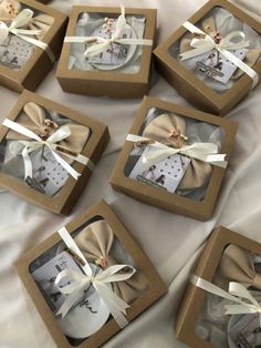 six brown boxes with white bows and pictures in them sitting on a tablecloth covered surface