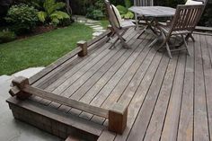 a wooden deck with chairs and table on it