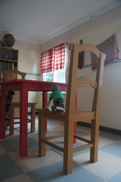 a child sitting on a chair at a table with a bookcase in the background