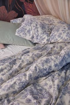 an unmade bed with blue and white sheets