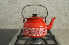 a red tea kettle sitting on top of a stove