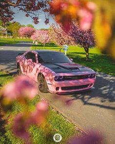 a pink and black car is parked on the side of the road in front of some trees