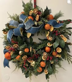 a wreath with oranges and berries hanging on a wall