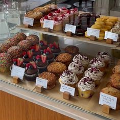 a display case filled with lots of different types of cupcakes and muffins