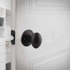 an open white closet with black knobs and shelves