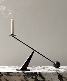 a black candle holder with a smokestack on it and a marble table top