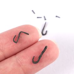 a person's fingers with black ink on them and an upside down hook in the middle