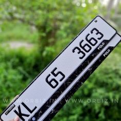 a person holding up a black and white license plate