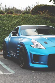 a blue sports car parked in front of a hedge