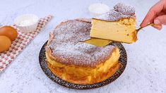 a person is cutting into a cake on a plate with some eggs and butter in the background