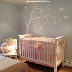 a baby's room with a tree painted on the wall and pink bedding