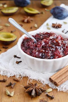 a bowl filled with cranberry sauce on top of a wooden table next to an apple