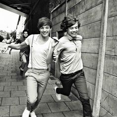 black and white photograph of two young men running down the street with their arms around each other