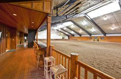 the inside of a horse barn with wooden flooring and stalls on either side of it