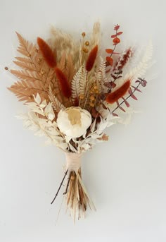 an arrangement of dried flowers and leaves on a white background