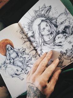 a person's hand on top of an open book with drawings in the pages