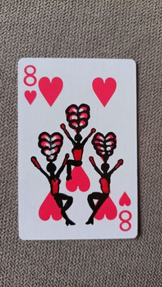 a playing card with the image of three women in red and black holding up hearts