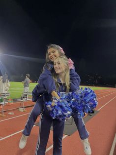 two cheerleaders on the sidelines with their pom poms