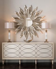 a white dresser with three lamps and a mirror on the wall above it in a living room