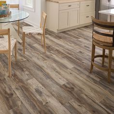 a kitchen and dining room with wood flooring, white cabinets and an island in the middle