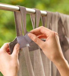 a woman is hanging curtains with her hands