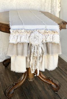 the table is covered with white linens and ruffled fabric, along with an old wooden