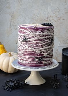 a halloween cake with white icing and black spider webs on the top is sitting on a pedestal