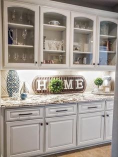 a kitchen filled with lots of white cupboards and counter top covered in glass doors