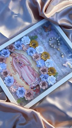 an image of the virgin mary surrounded by blue roses on a pink satin background with butterflies