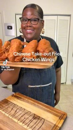 a woman holding a tray with chicken wings on it and the words, chinese take out fried chicken wings