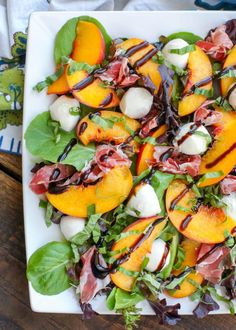 a white plate topped with sliced peaches and greens