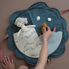 a child is playing with a stuffed animal on the floor next to a blue pillow