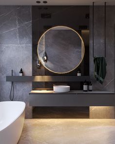 a bathroom with a large round mirror above the bathtub and two sinks in front of it