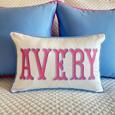 two blue and pink pillows with the word avery on them sitting on top of a bed