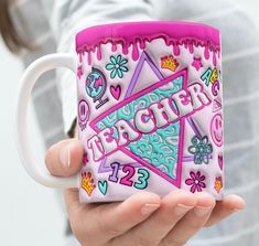 a woman is holding a coffee mug with the words teacher on it and decorated in different colors