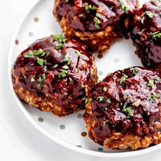 four meat patties covered in ketchup on a white plate