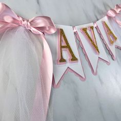 a pink and white banner with the word ava spelled in gold glitter letters on it