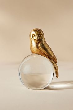 a gold owl figurine sitting on top of a clear glass ball ornament