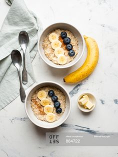 two bowls of oatmeal with bananas and blueberries are on the table