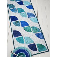 a table runner with blue and green circles on it next to a plate, fork and spoon