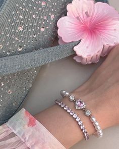 a woman's arm with two bracelets and a flower