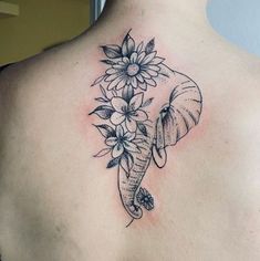 an elephant and flowers tattoo on the back of a woman's upper back shoulder